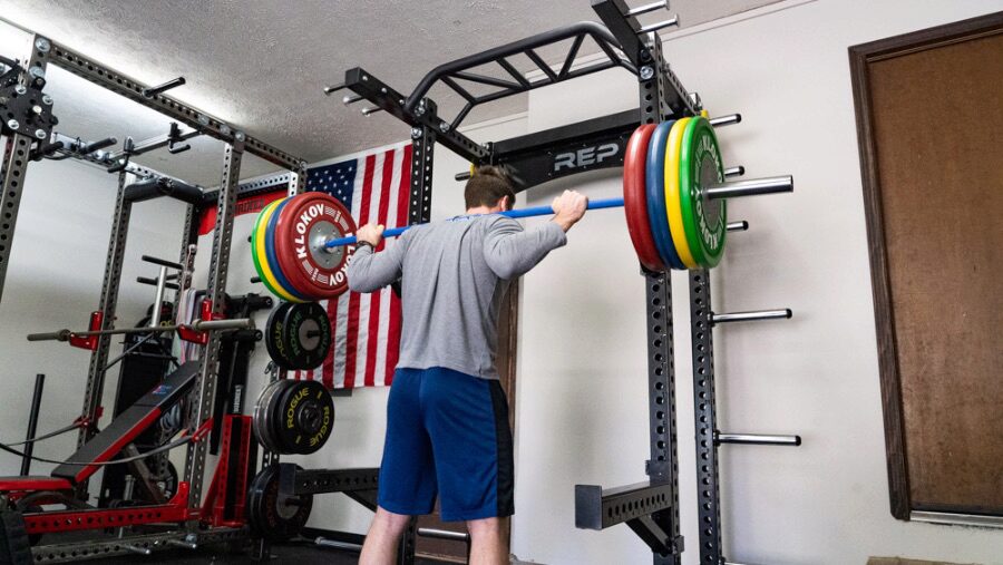 Man squatting out of a half rack at home