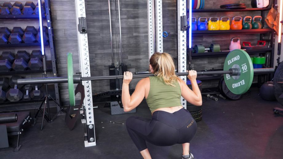 A person squatting with the Rep Helios squat bar