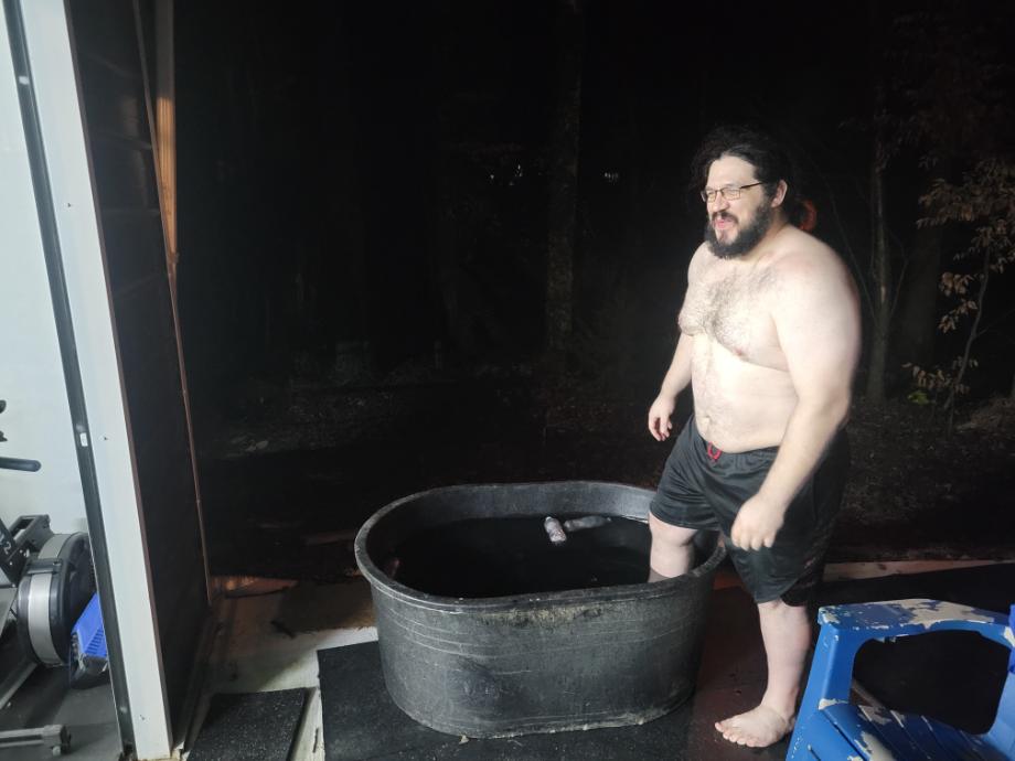 Man stepping into a Tuff Stuff Stock Tank filled with ice water