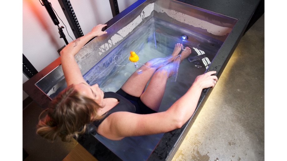 Our tester in the Sun Home Sauna Cold Plunge Pro, with a blue light shining.