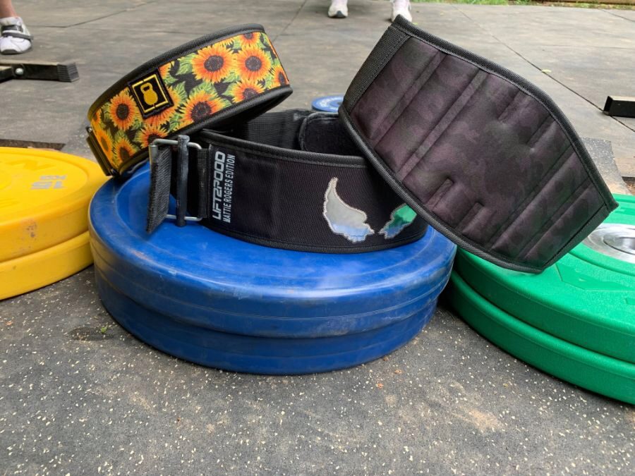 Three 2POOD belts resting on weight plates