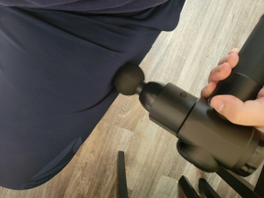 A man uses the TOLOCO massage gun to loosen up the IT band of his leg