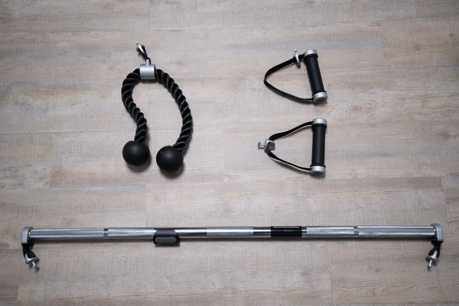 Tonal accessories: smart rope attachment, smart handle attachments, and smart bar attachment lying on a wood floor