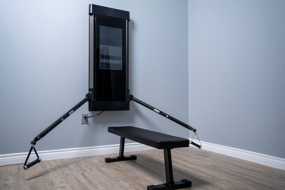 Tonal trainer with the arms positioned down in front of the Tonal weight bench