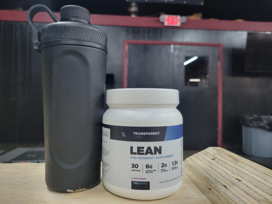 A black shaker bottle rests next to a container of Transparent Labs Pre-Workout.
