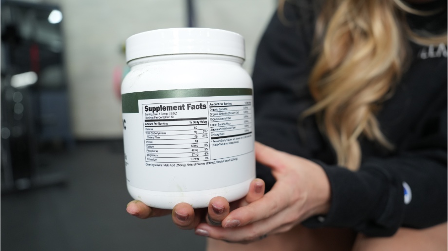 Someone holding a container of Transparent Labs Prebiotic Greens with the supplement facts label showing