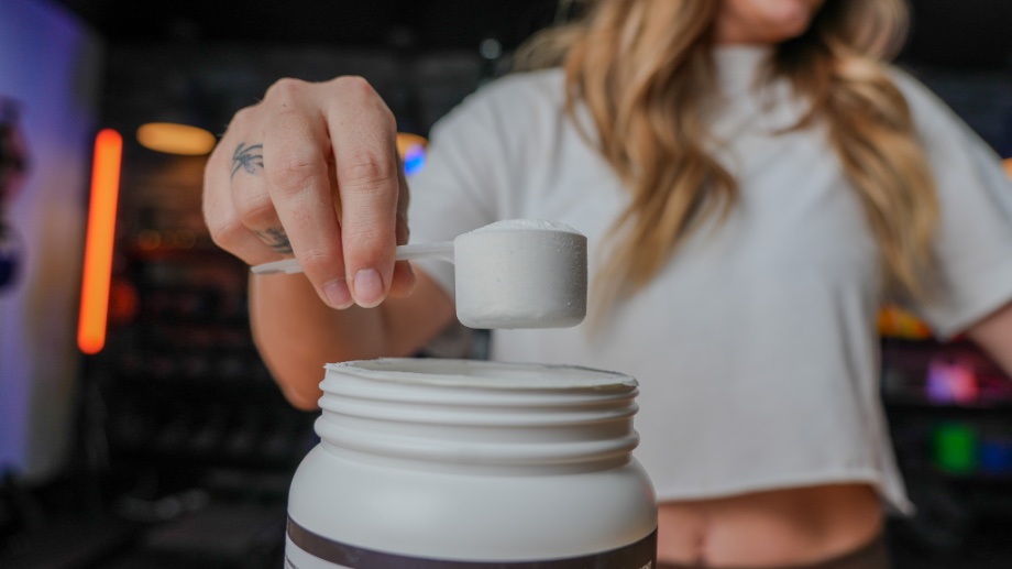 A woman holds up a full scoop of Transparent Labs Stim-Free Pre-Workout.