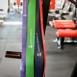 Gymreapers Resistance Bands in various sizes and colors hanging from piece of workout equipment.