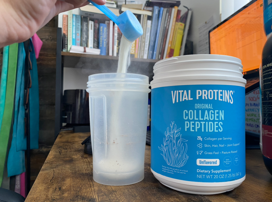 Person pouring a scoop of Vital Collagen Protein into a shaker cup while next to the protein powder container