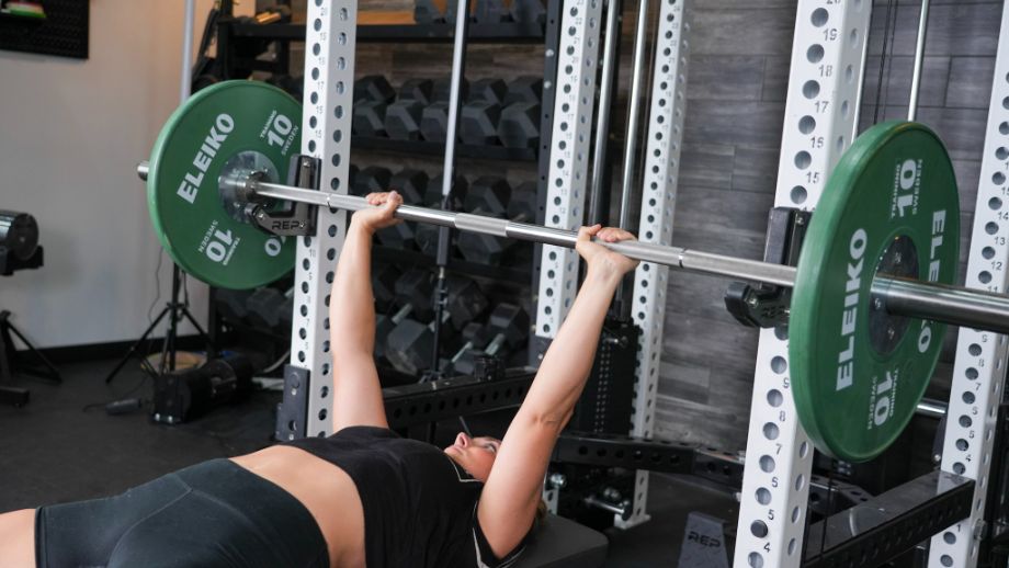 Woman benching with the REP Fitness Double Black Diamond Power Bar