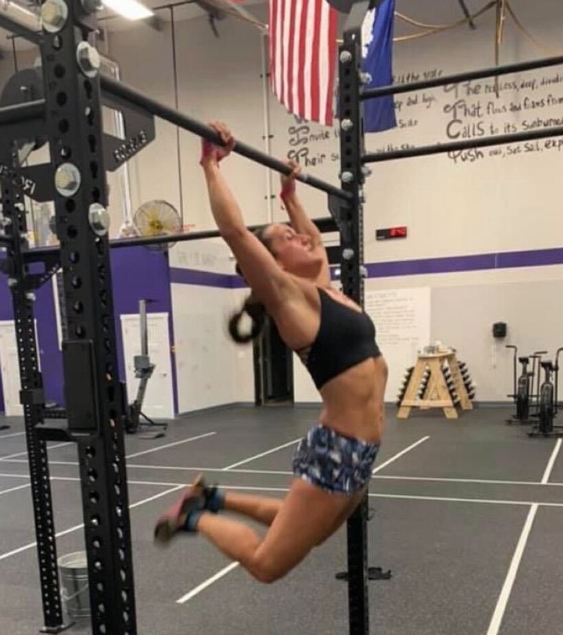 woman doing kipping pull-ups in a gym