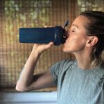 An image of a woman drinking 1st phorm collagen out of a shaker