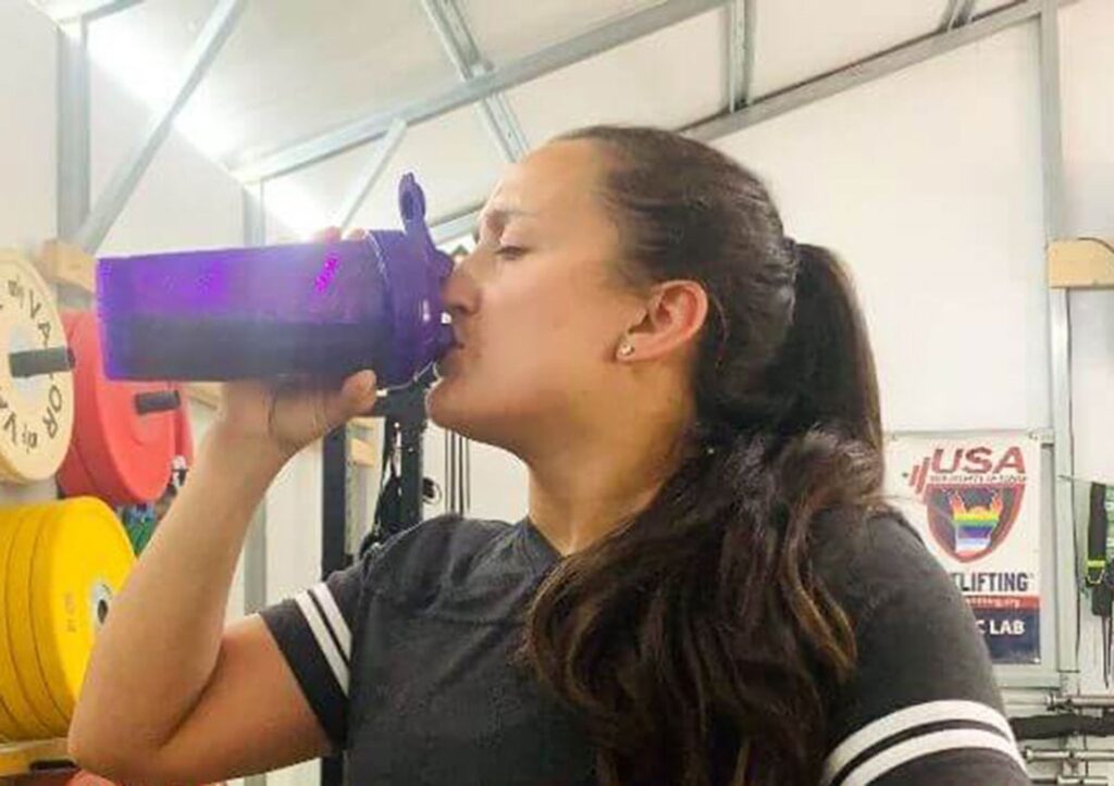 A woman is shown drinking from a shaker cup.