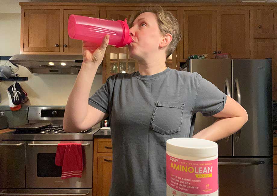 Woman drinks a shaker cup of AminoLean Pre-Workout