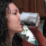 A woman is shown drinking coffee from a ceramic mug.