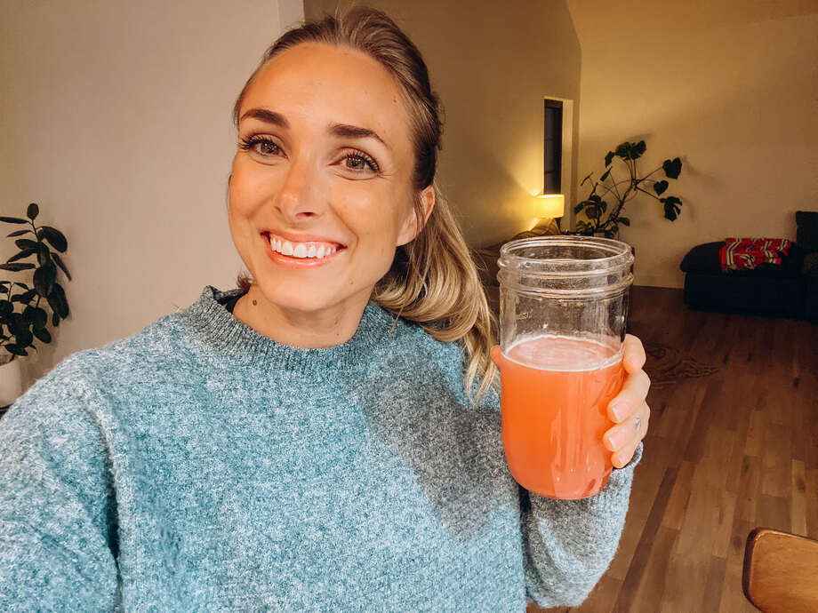 woman holding a glass of six star pre workout powder in a glass with water