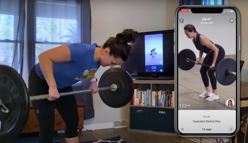 Woman doing barbell rows with an online personal trainer in her living room