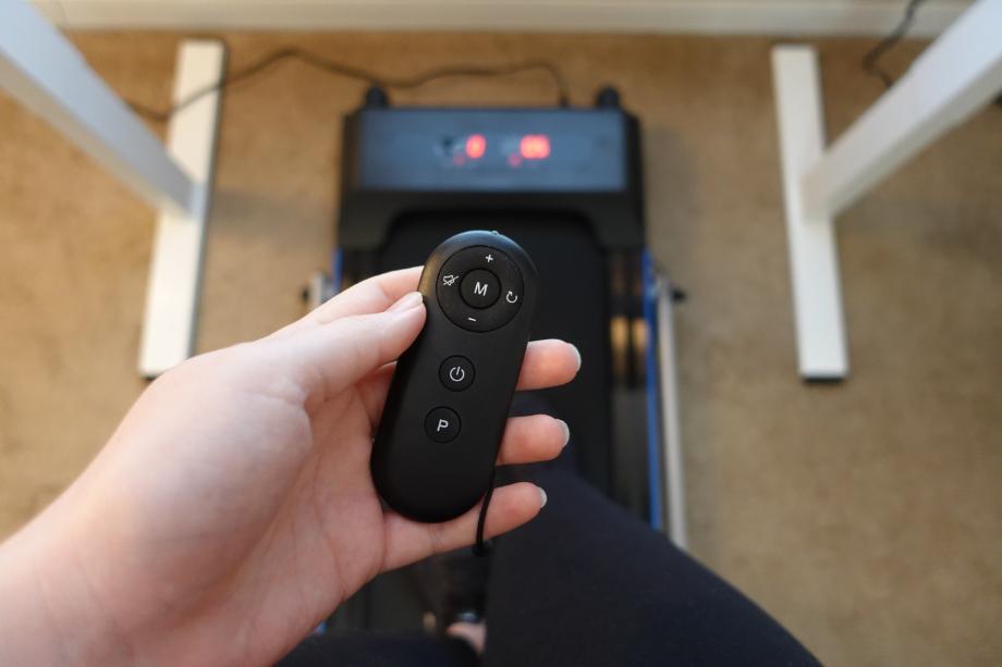 A hand is shown holding a remote with the REDLIRO Under Desk Treadmill in the background.