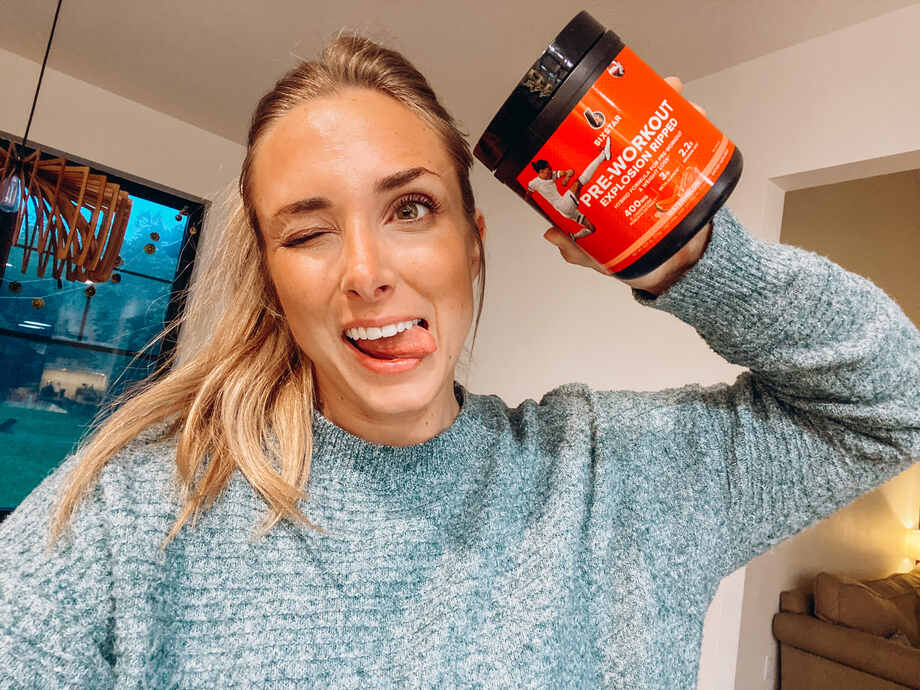 woman holding a tub of six star pre workout powder