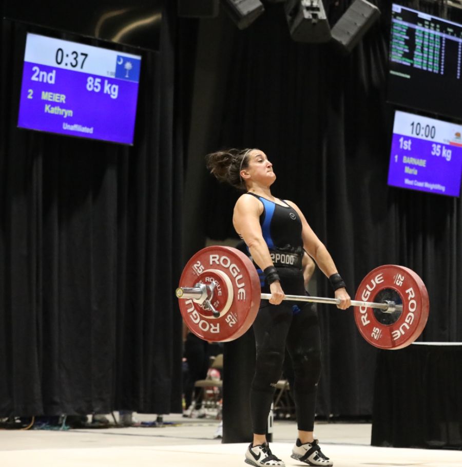 A woman lifting on a platform wearing a 2POOD weightlifting belt