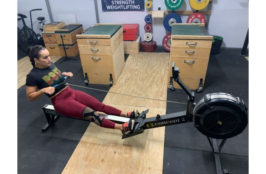 woman rowing with copper knee sleeve