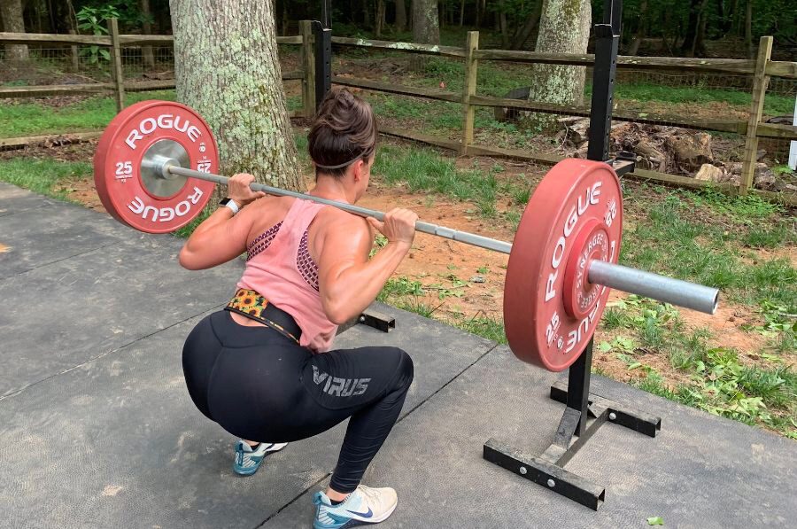Woman squatting a barbell while wearing a 2POOD Petite Belt.