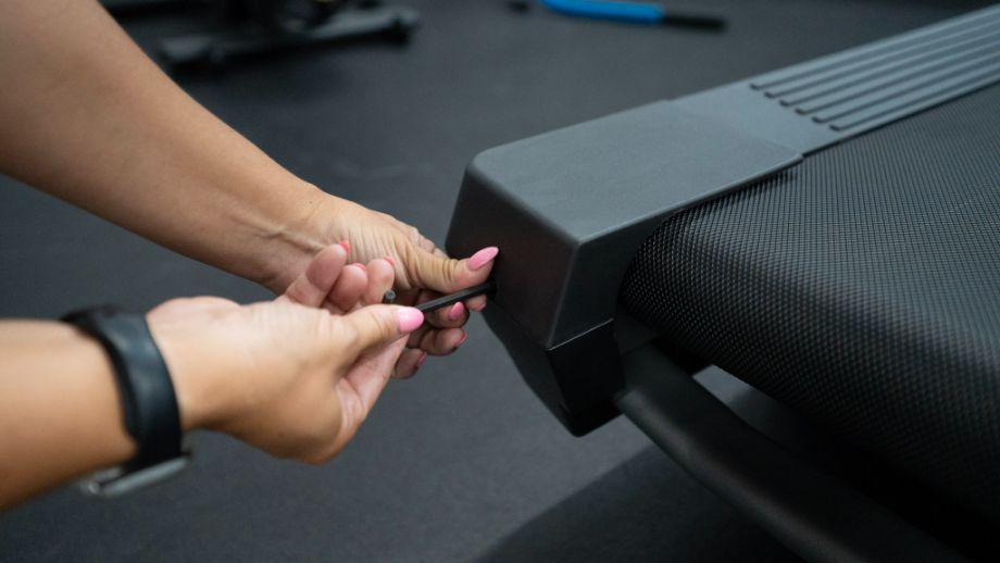 woman using tool to adjust NordicTrack treadmill belt