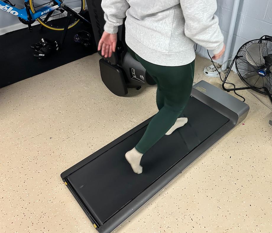 A woman can be seen from the torso down walking on a WalkingPad Treadmill