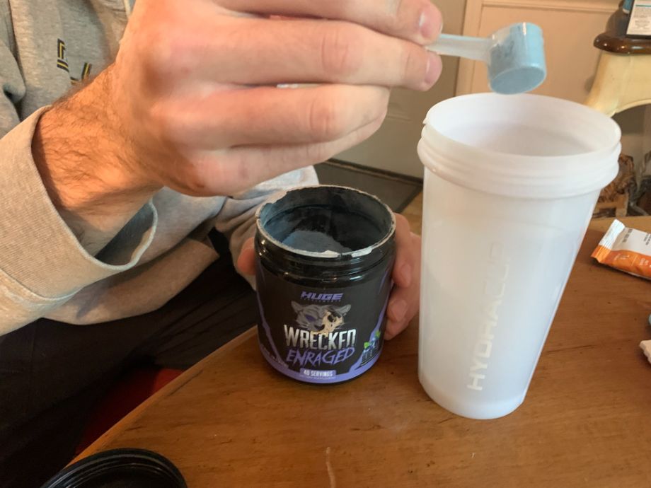Wrecked Enraged pre-workout being scooped into a shaker bottle