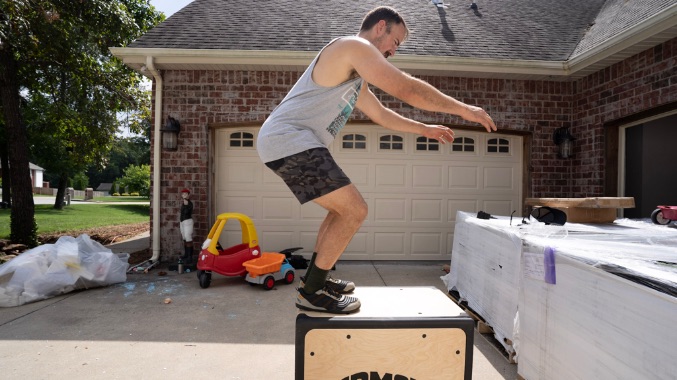 Coop doing a box jump while wearing the Xero 360 shoes. He is outside of his home and children's toys are in the background.