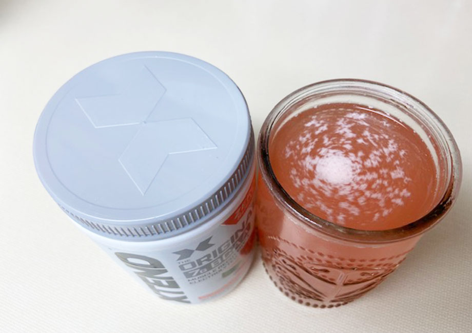 XTEND BCAA container next to the mixed drink in a glass